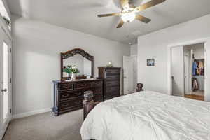 Bedroom with light colored carpet, a ceiling fan, and a spacious closet