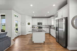 Kitchen with stainless steel appliances, white cabinets, open floor plan, tasteful backsplash, and a center island