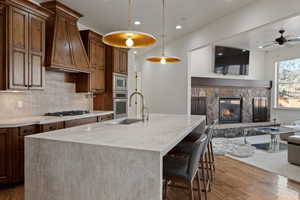 Kitchen featuring light stone counters, hardwood / wood-style flooring, a breakfast bar area, and a ceiling fan