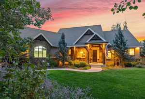 Craftsman-style house featuring stone siding, covered porch, a front yard, and a shingled roof