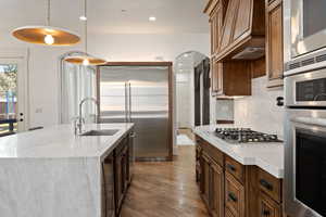 Kitchen with light stone countertops, built in appliances, dark wood-style floors, and wine cooler