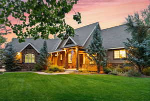Craftsman house with stone siding, a lawn, a porch, and a shingled roof