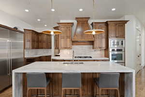 Kitchen featuring light wood finished floors, light stone countertops, and built in appliances