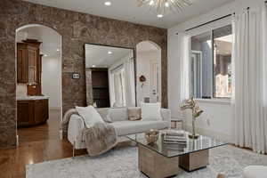 Living room featuring arched walkways, wood finished floors, and recessed lighting