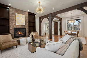 Living area with arched walkways, built in features, hanging lights, light wood-style flooring, and a fireplace