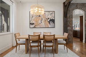 Dining room featuring hanging lights, arched walkways, and light wood-style flooring