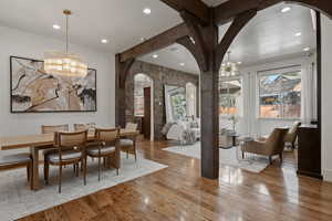 Dining room featuring suspended lighting, arched walkways, and light wood-style floors