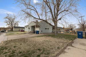 View of side of property featuring a yard, a residential view, a chimney, and concrete driveway