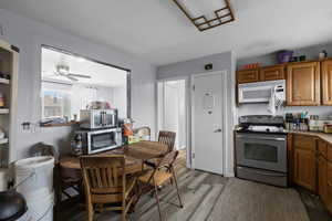 Kitchen featuring stainless steel appliances, wood finish cabinets, dark wood-style flooring, ceiling fan, and light countertops