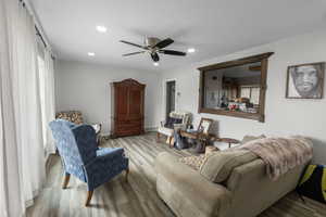 Living area with wood finished floors, a ceiling fan, healthy amount of natural light, and recessed lighting