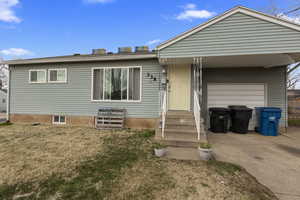 View of front of property with driveway, a front yard, an attached garage, and entry steps