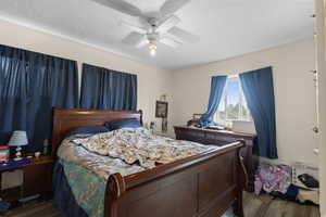 Bedroom featuring dark wood-type flooring, a ceiling fan, and a textured ceiling