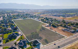 Aerial overview of property's location with property parcel outlined, nearby suburban area, and a mountain backdrop