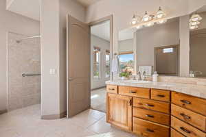Bathroom featuring vanity, tiled shower, and light tile patterned floors