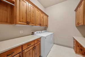 Laundry room featuring cabinet space, washing machine and clothes dryer, and light tile patterned floors