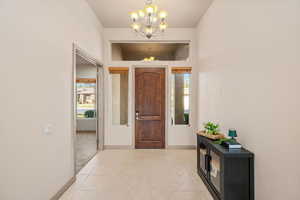 Entryway featuring light tile patterned flooring, suspended lighting, and inlaid floor details