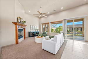 Living area with a high ceiling, a glass covered fireplace, a ceiling fan, and recessed lighting
