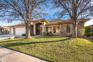 View of front facade featuring stone siding, a garage, stucco siding, driveway, and a front yard
