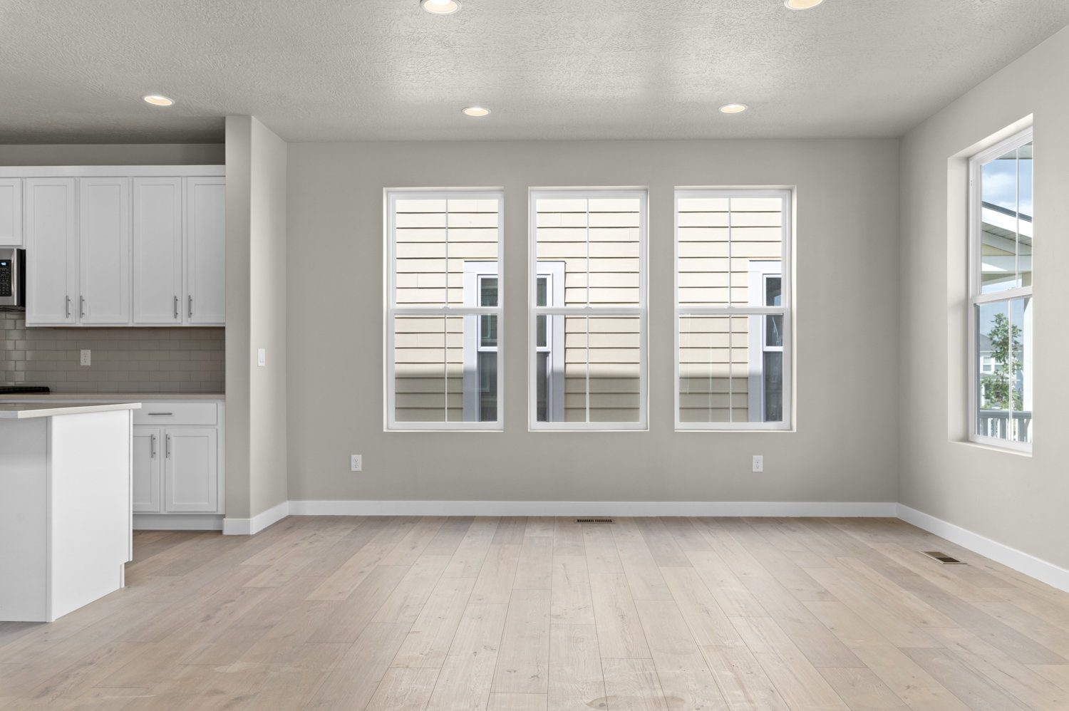 Kitchen featuring white cabinets, decorative backsplash, light wood-style flooring, a textured ceiling, and recessed lighting