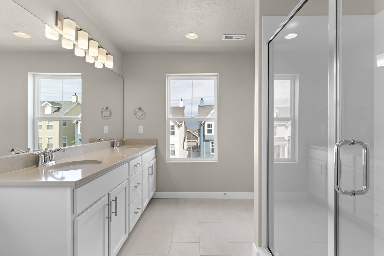 Bathroom with double vanity, a stall shower, recessed lighting, healthy amount of natural light, and light tile patterned floors
