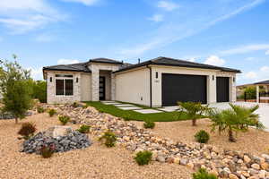 Prairie-style home featuring stone siding, concrete driveway, an attached garage, and stucco siding
