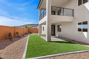 Fenced backyard featuring a patio area, a balcony, and a mountain view