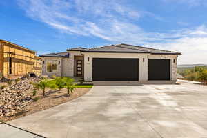 Prairie-style home featuring a tile roof, an attached garage, stucco siding, driveway, and stone siding