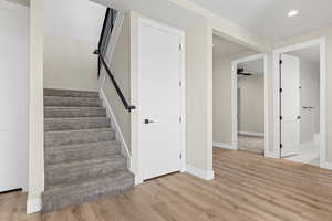 Staircase with wood finished floors, a ceiling fan, and recessed lighting