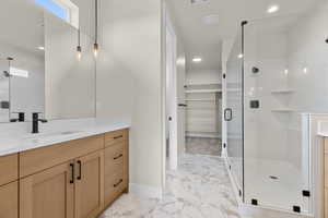 Full bathroom featuring vanity, a walk in closet, a marble finish shower, recessed lighting, and light marble finish floors