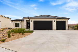 Prairie-style home featuring stone siding, an attached garage, stucco siding, and driveway