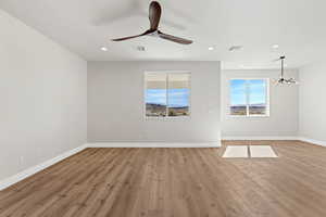 Empty room with light wood-type flooring, a ceiling fan, and suspended lighting