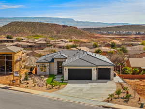 View of front of house with an attached garage, a residential view, stone siding, driveway, and a mountain view