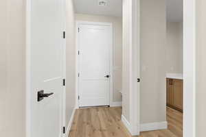 Hallway with light wood-style flooring and baseboards