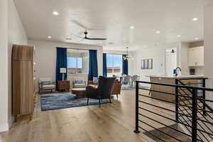 Living room with ceiling fan, light wood-style flooring, and recessed lighting