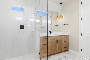 Full bath with vanity, a marble finish shower, and light marble finish flooring