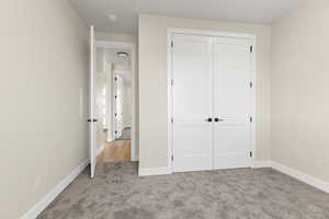 Unfurnished bedroom with light colored carpet and a closet