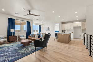 Living area featuring light wood finished floors, a ceiling fan, and suspended lighting