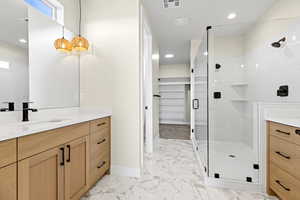 Bathroom featuring vanity, recessed lighting, a marble finish shower, a walk in closet, and light marble finish flooring