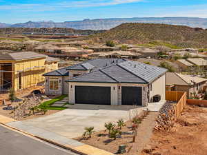 View of front of property with a residential view, a garage, stone siding, concrete driveway, and a mountain view