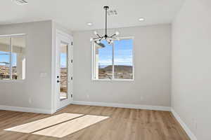 Unfurnished dining area featuring a chandelier and light wood finished floors