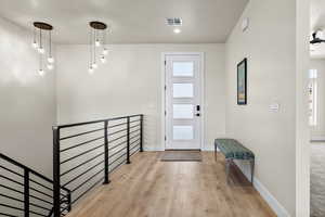Foyer with light wood finished floors and baseboards