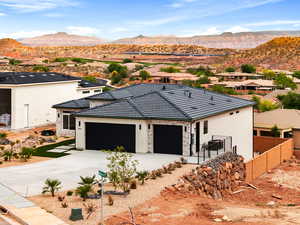 View of front facade with stone siding, an attached garage, concrete driveway, a mountain view, and stucco siding