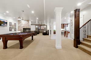 Game room featuring light colored carpet, a stone fireplace, billiards table, recessed lighting, and decorative columns