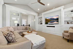 Living room featuring built in features, ceiling fan, light carpet, and suspended lighting