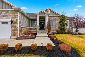 Craftsman inspired home featuring board and batten siding, stone siding, a garage, and a front yard