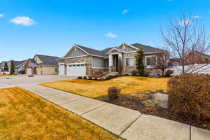 Craftsman inspired home with stone siding, board and batten siding, a front lawn, an attached garage, and concrete driveway