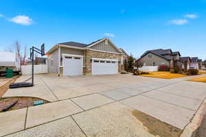 View of home's exterior with board and batten siding, stone siding, driveway, an attached garage, and a residential view
