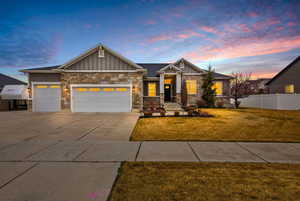 Craftsman-style house with board and batten siding, an attached garage, driveway, and stone siding