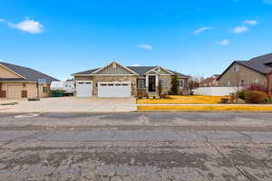 Craftsman house featuring board and batten siding, stone siding, a garage, driveway, and covered porch