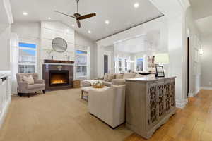 Living room featuring a tile fireplace, a ceiling fan, lofted ceiling, recessed lighting, and light wood-type flooring